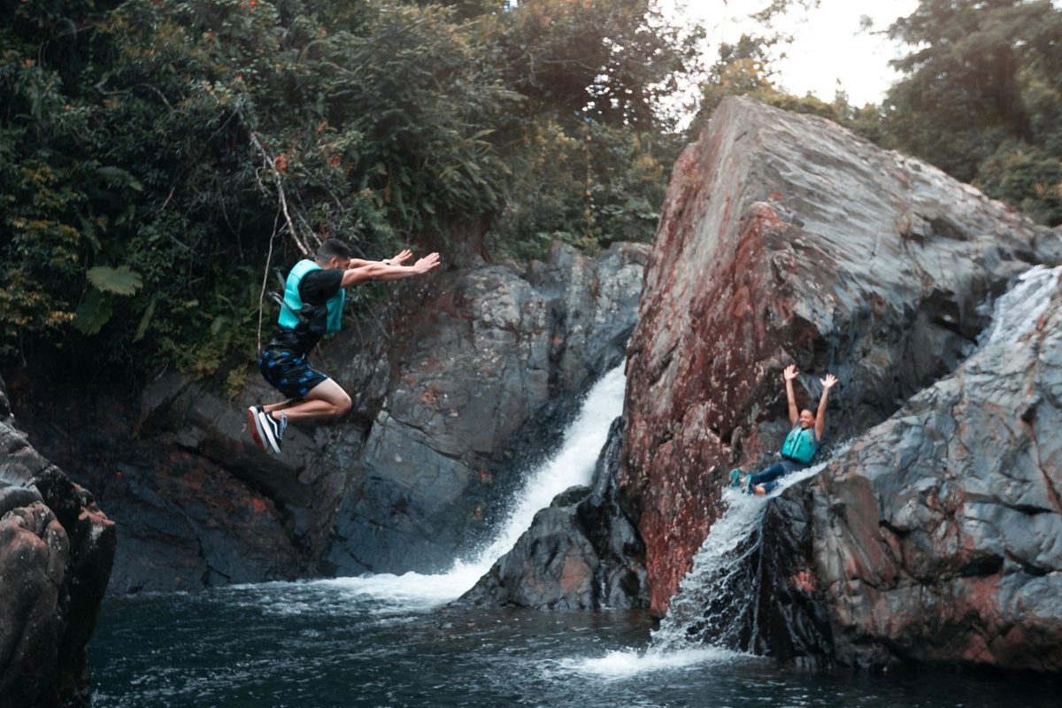 people sliding down a El Yunque's natural water slide and rope swinging into the natural pool